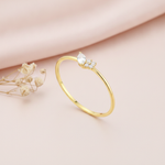 gold ring with a marquise-cut stone and a cluster of round clear accents on blush silk with dried flowers