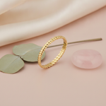 gold twisted rope ring styled with a rose quartz stone and eucalyptus leaves on a blush background