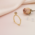 gold beaded ring with a crowned center stone, styled with a dried rose and clear stones on a blush background