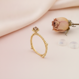 gold beaded ring with a crowned center stone, styled with a dried rose and clear stones on a blush background
