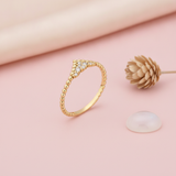 gold beaded ring with a chevron of pave stones, styled with a dried flower on a pink background