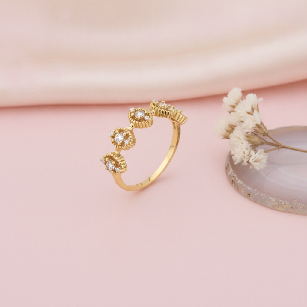 gold ring with beaded marquise stations set with clear stones, styled with a dried flower and an agate slice on a pink background