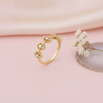 gold ring with beaded marquise stations set with clear stones, styled with a dried flower and an agate slice on a pink background