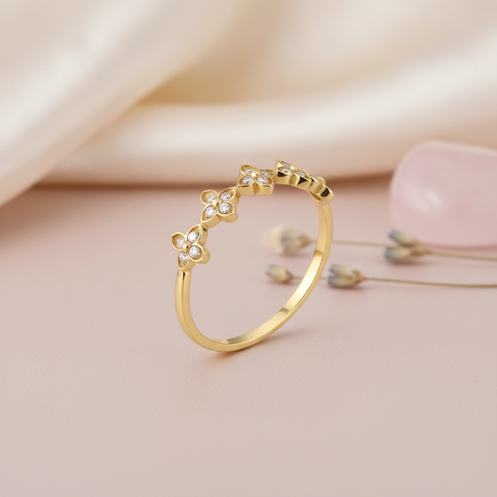 gold ring with pave-set four-petal flower motifs, styled with dried lavender and a pink stone on a blush background