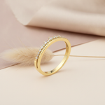 gold ring with a crest of pave clear stones, styled with dried grass on a cream background