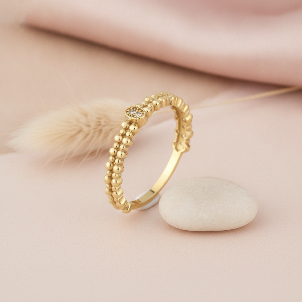 gold beaded ring with a pave clear stone accent, styled with a dried flower stem on a blush background