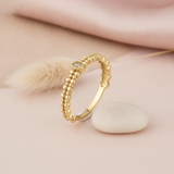 gold beaded ring with a pave clear stone accent, styled with a dried flower stem on a blush background