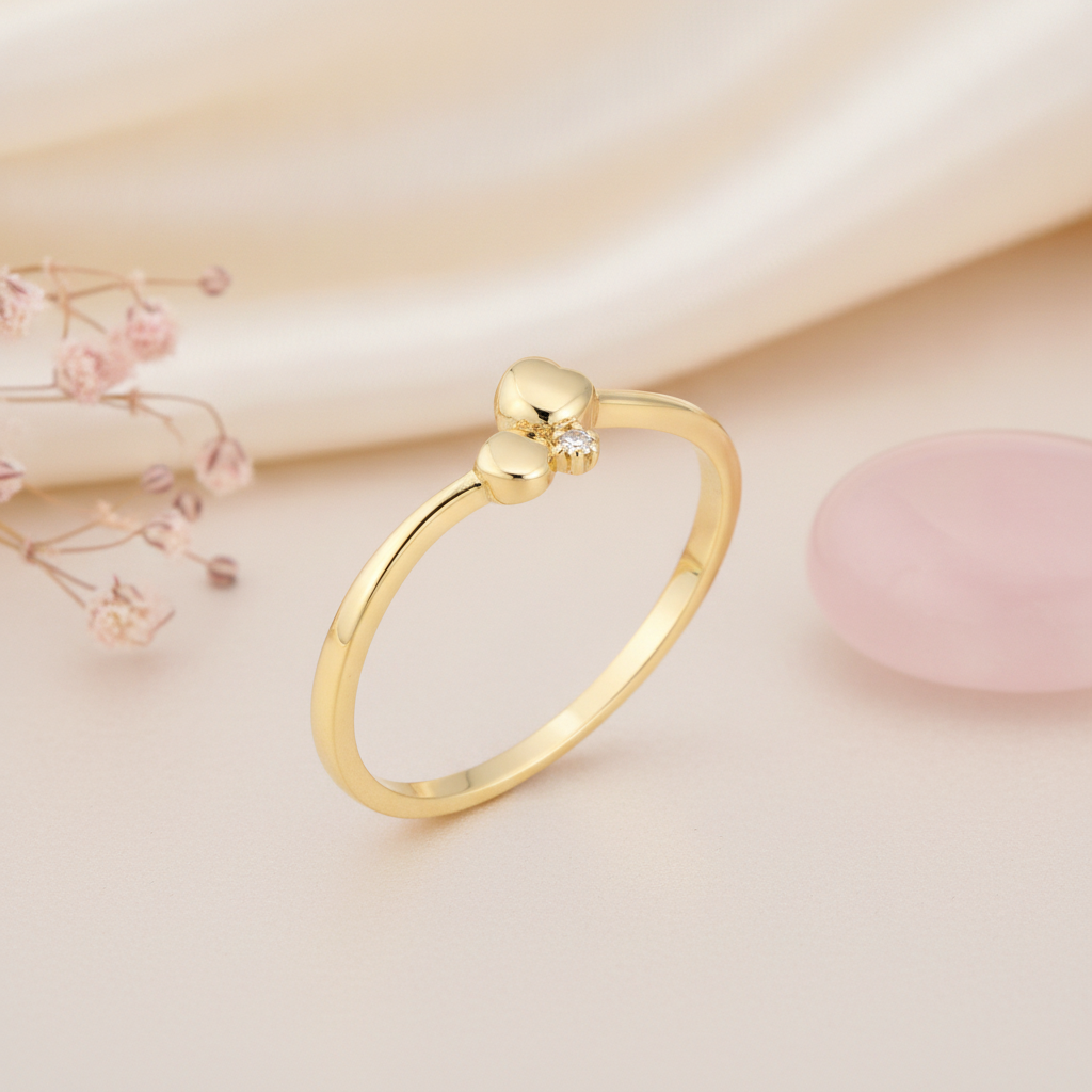 gold ring with two polished spheres and a clear stone accent, styled with dried baby's breath and a pink stone on a blush background
