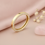 gold band with a row of pave clear stones along the edge, styled with dried baby's breath and a pink stone on a blush background