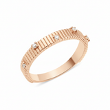 rose gold ribbed ring set with clear stones on white background