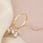 gold ring with raised beaded texture, styled with dried baby's breath on a blush background