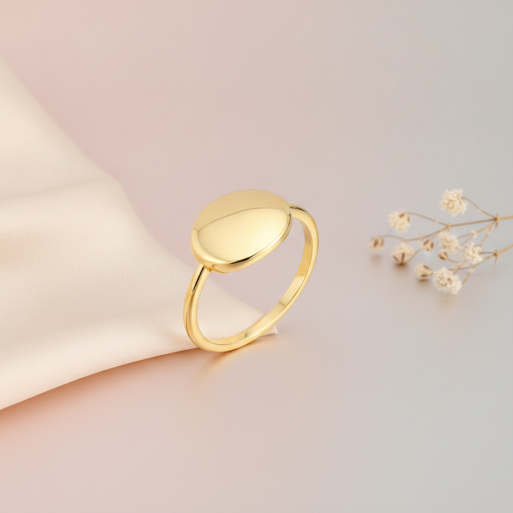 gold ring with a polished oval top, styled with dried baby's breath on a blush and gray background
