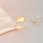 gold ring with a polished oval top, styled with dried baby's breath on a blush and gray background