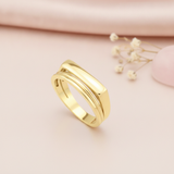 gold ring with a flat bar floating over a curved band, styled with a eucalyptus leaf and a pink stone on a cream background