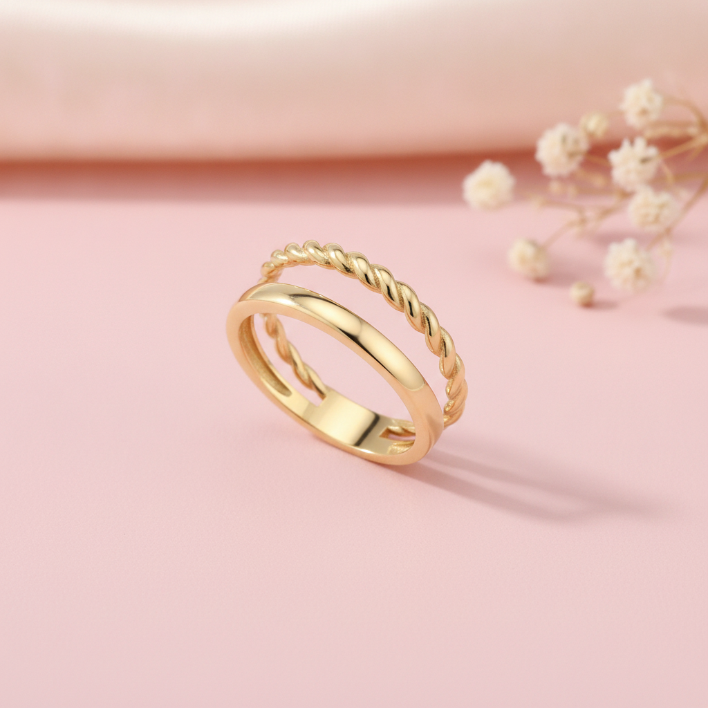 gold double-band ring pairing a smooth surface with a twisted rope strand, styled with dried baby's breath on a blush background