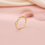gold ring with open paperclip chain links, styled with dried grass and a pink stone on a blush background