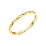 yellow gold ring with carved circle and cross texture on white background