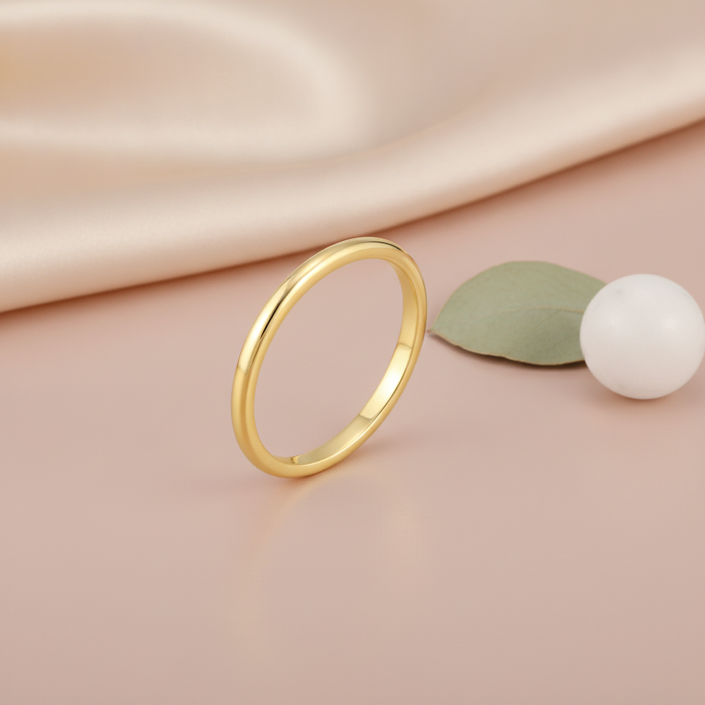 gold Linea band ring on a blush pink background with draped satin fabric and a leaf accent