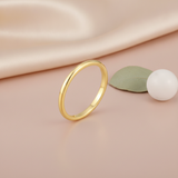 gold Linea band ring on a blush pink background with draped satin fabric and a leaf accent