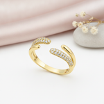 gold open bypass Solis ring with pave-set stones on a pink background with draped satin fabric and a rose quartz stone