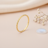 slender etched gold Raya ring on a blush background with draped satin fabric and a moonstone cabochon