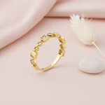 geometric gold Tessera cube ring with clear stones on a pink background with draped satin fabric and a dried flower sprig