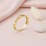 geometric gold Tessera cube ring with clear stones on a pink background with draped satin fabric and a dried flower sprig