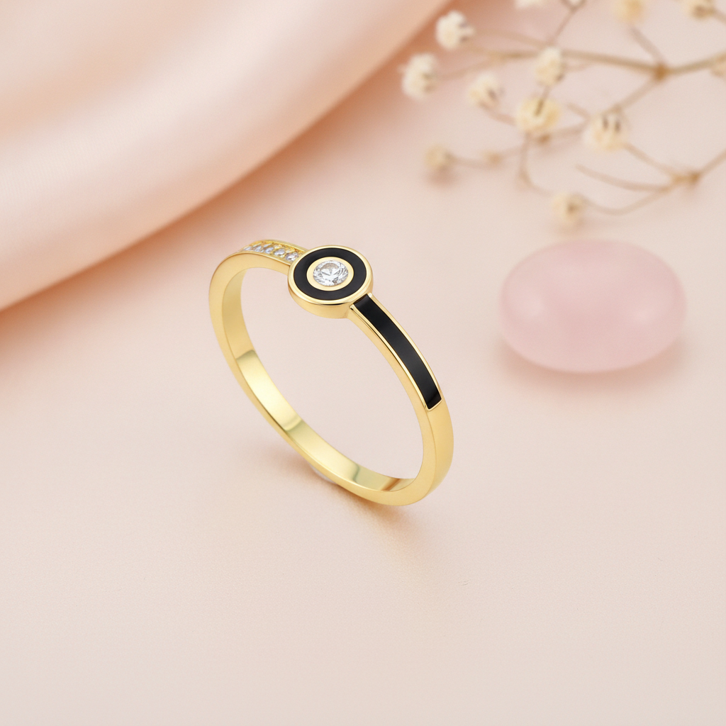 gold Oculus ring with black enamel halo and clear stone on a blush background with draped satin fabric and a pink stone accent