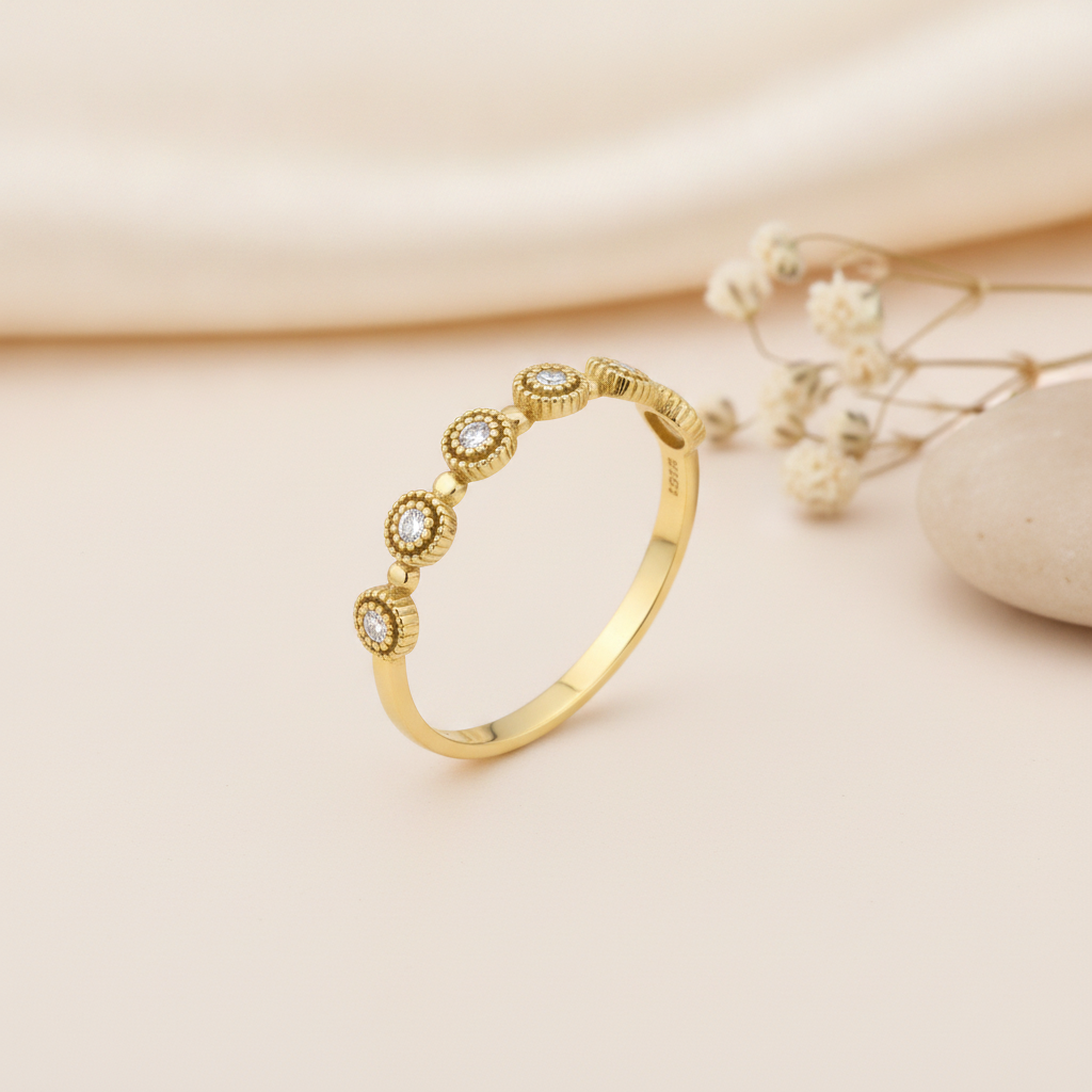 gold Aurelia station ring with milgrain detail on a cream background with draped satin fabric and dried baby's breath