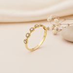 gold Aurelia station ring with milgrain detail on a cream background with draped satin fabric and dried baby's breath