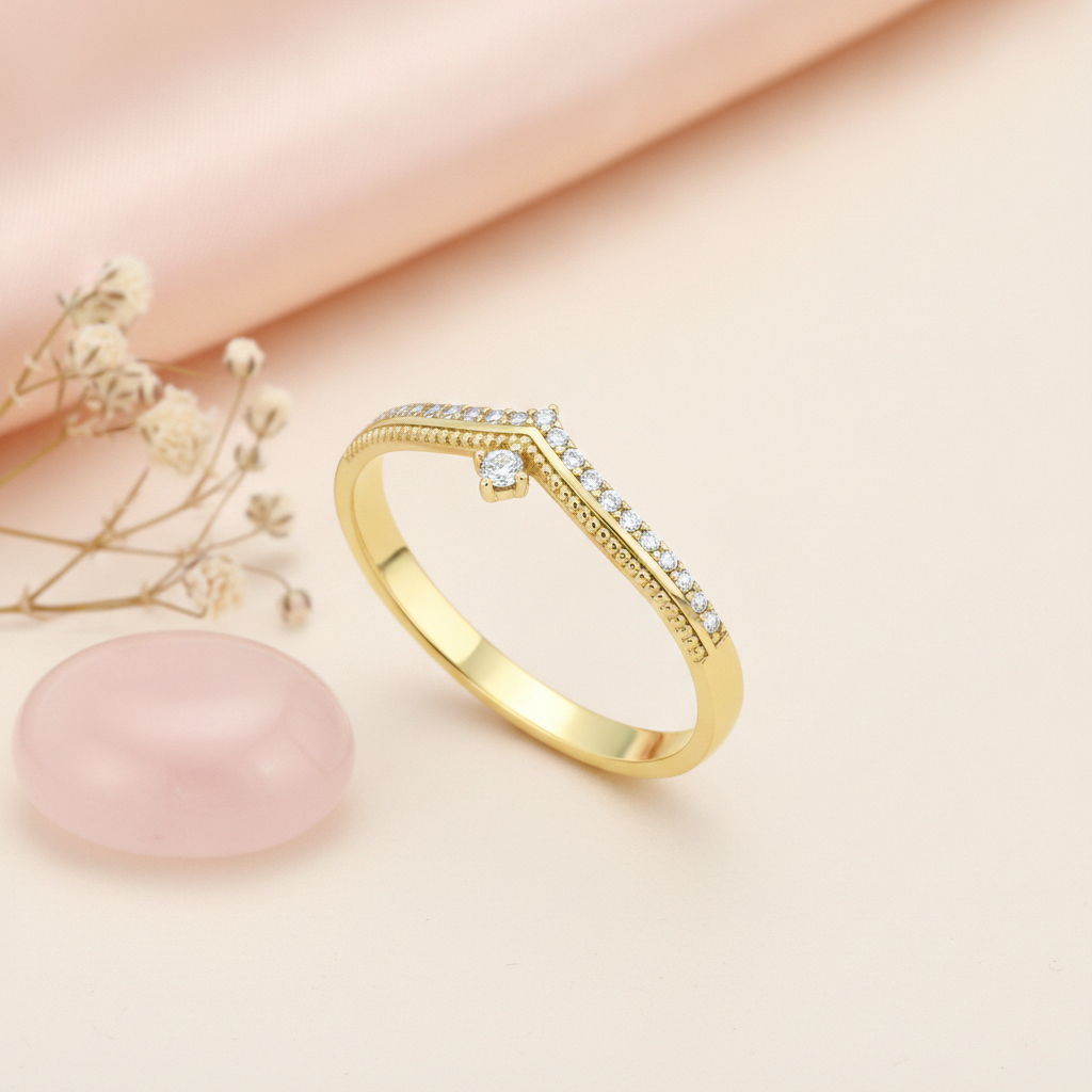 gold chevron ring with White CZ stones and a single suspended stone on a cream background with draped satin fabric and a rose quartz stone