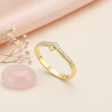 gold chevron ring with White CZ stones and a single suspended stone on a cream background with draped satin fabric and a rose quartz stone
