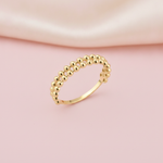 double row of gold sphere beads forming a ring on a blush pink background with draped satin fabric