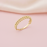 double row of gold sphere beads forming a ring on a blush pink background with draped satin fabric