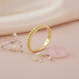 double row gold beaded ring with larger and smaller spheres on a blush background with dried baby's breath and a rose quartz stone