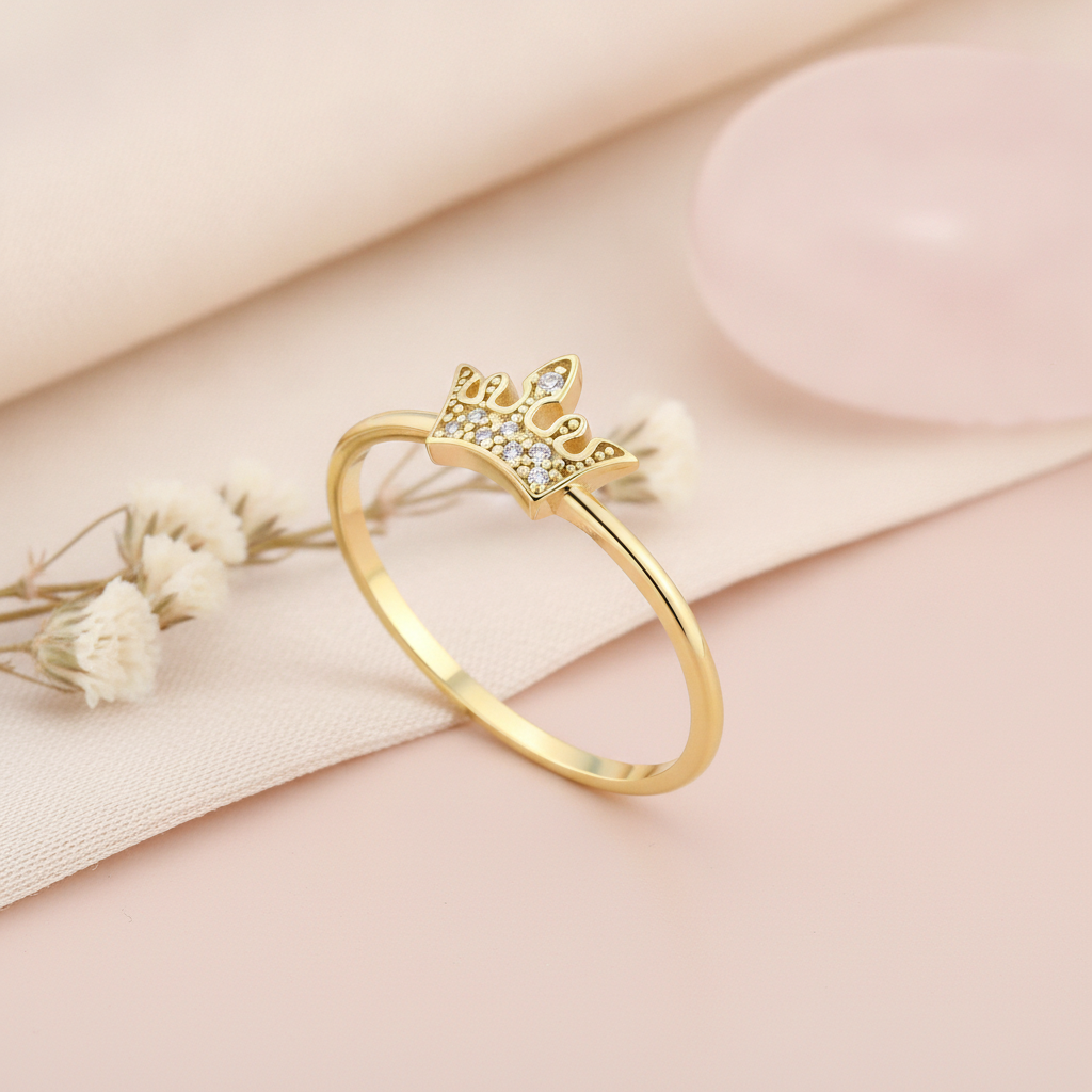 gold crown ring with a cluster of White CZ stones on a blush background with draped fabric, baby's breath, and a pink stone
