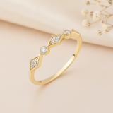 gold ring with kite-shaped clustered stone stations and bezel-set stones on a cream background with dried baby's breath