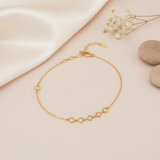 gold chain bracelet with four square White CZ stone stations and a single accent stone on a blush background with baby's breath and stones