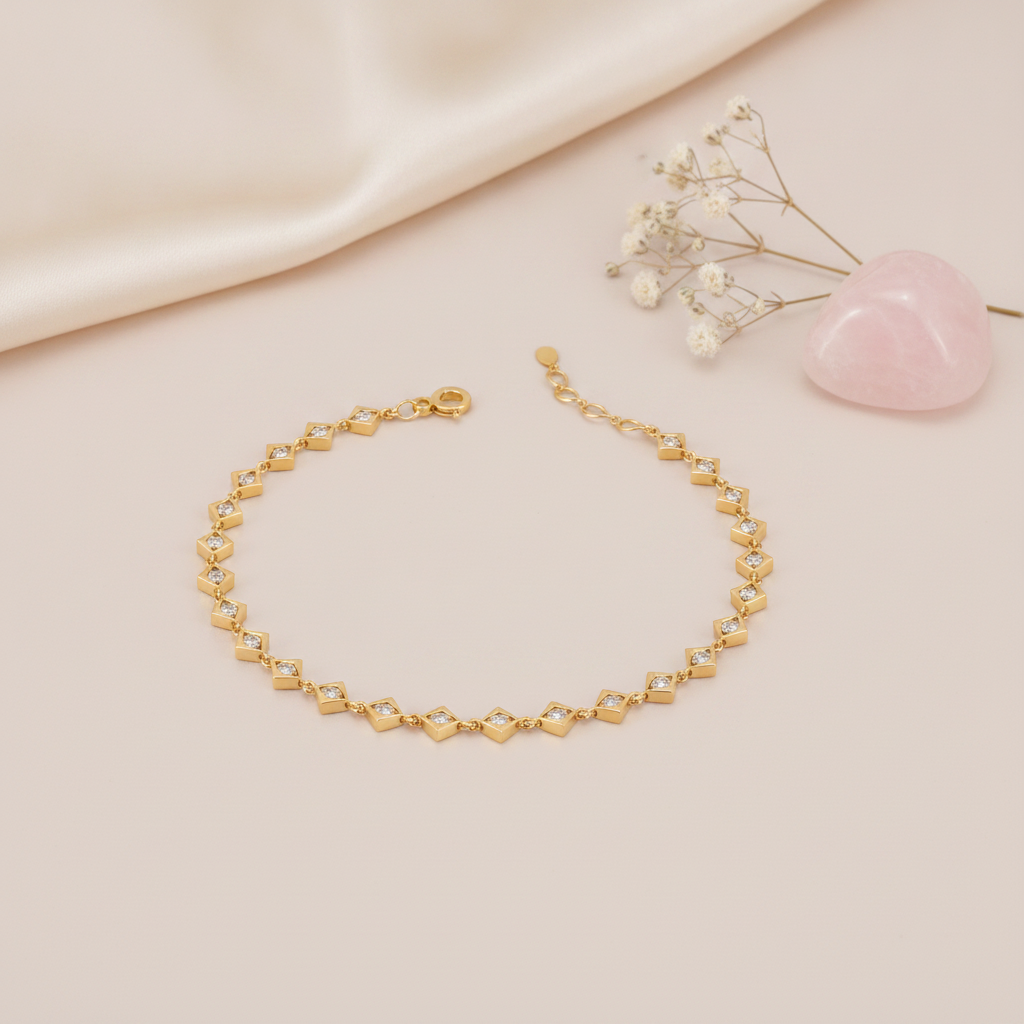 gold linked kite frame bracelet with stones on a blush background with draped satin fabric and a rose quartz heart