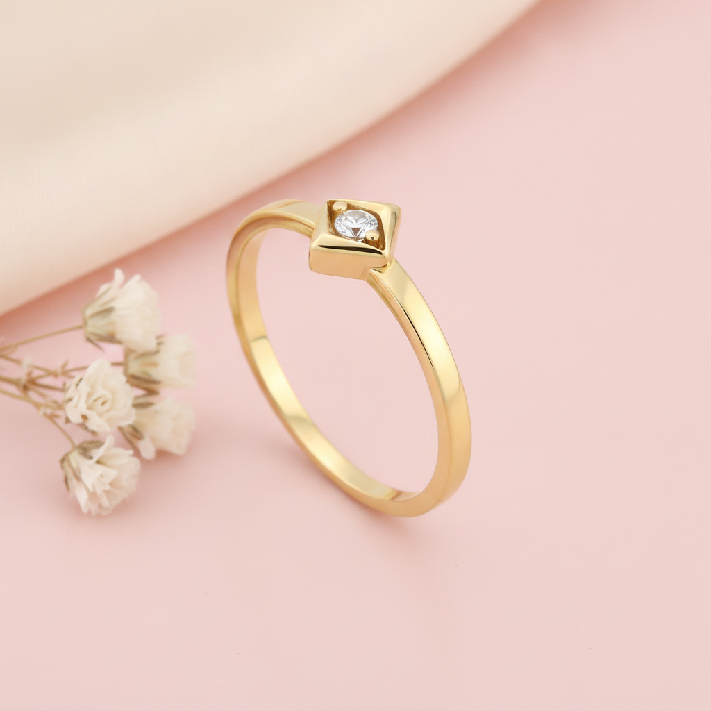 slender gold ring with a single White CZ stone in a square bezel on a pink background with dried baby's breath