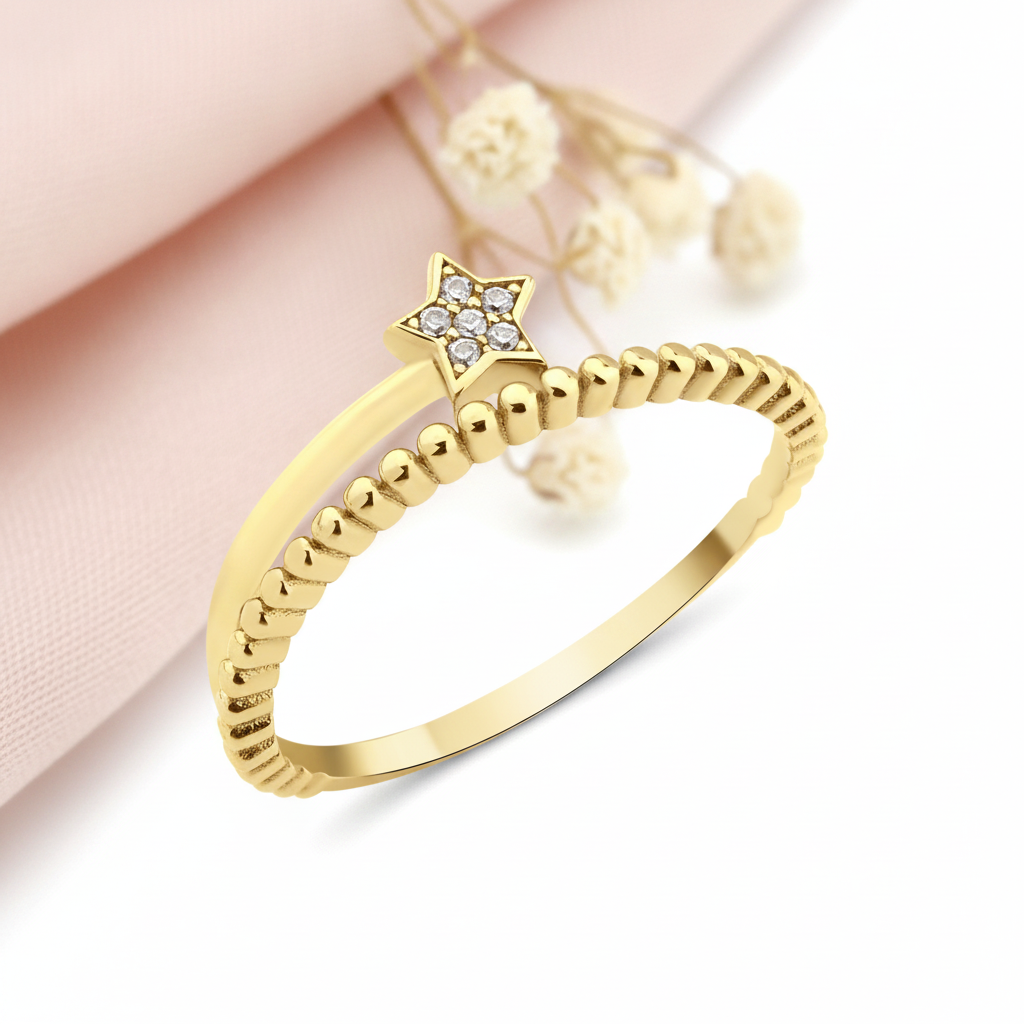 gold ring with a beaded band and a stone-set star on a blush backdrop with a soft feather and a stone