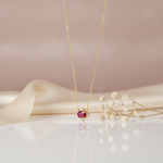 gold pendant necklace with a horizontal oval red gemstone on a cream backdrop with dried baby's breath