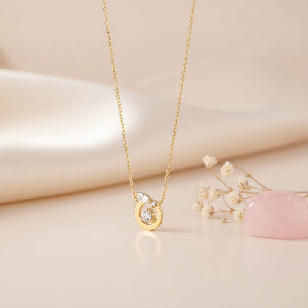 gold circle pendant necklace with a round center stone on a cream backdrop with dried baby's breath and a rose quartz stone