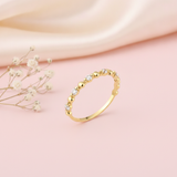 gold heart band ring with clear stones displayed on pink satin with dried baby's breath