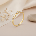 gold graduated stone ring displayed on cream and pink background with dried flowers and a smooth stone