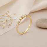 gold graduated stone ring displayed on cream and pink background with dried flowers and a smooth stone