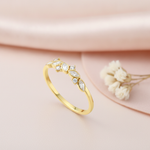 gold ring with marquise and round White CZ stones displayed on pink satin with dried flowers