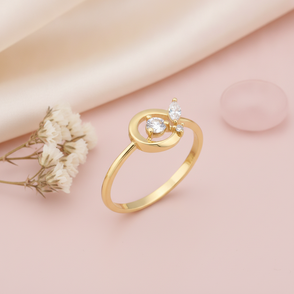 gold open circle ring with three stones displayed on pink satin with dried baby's breath and a pink stone
