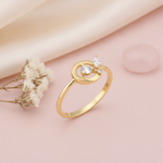 gold open circle ring with three stones displayed on pink satin with dried baby's breath and a pink stone