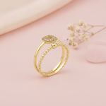 gold double band ring with pave cushion halo displayed on pink satin with dried baby's breath
